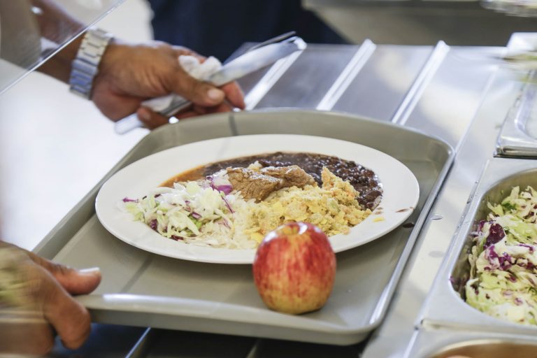 Pessoa serve um prato de comida num restaurante a quilo
